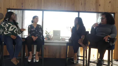 Four women sitting on a stage having an engaging and hilarious conversation.